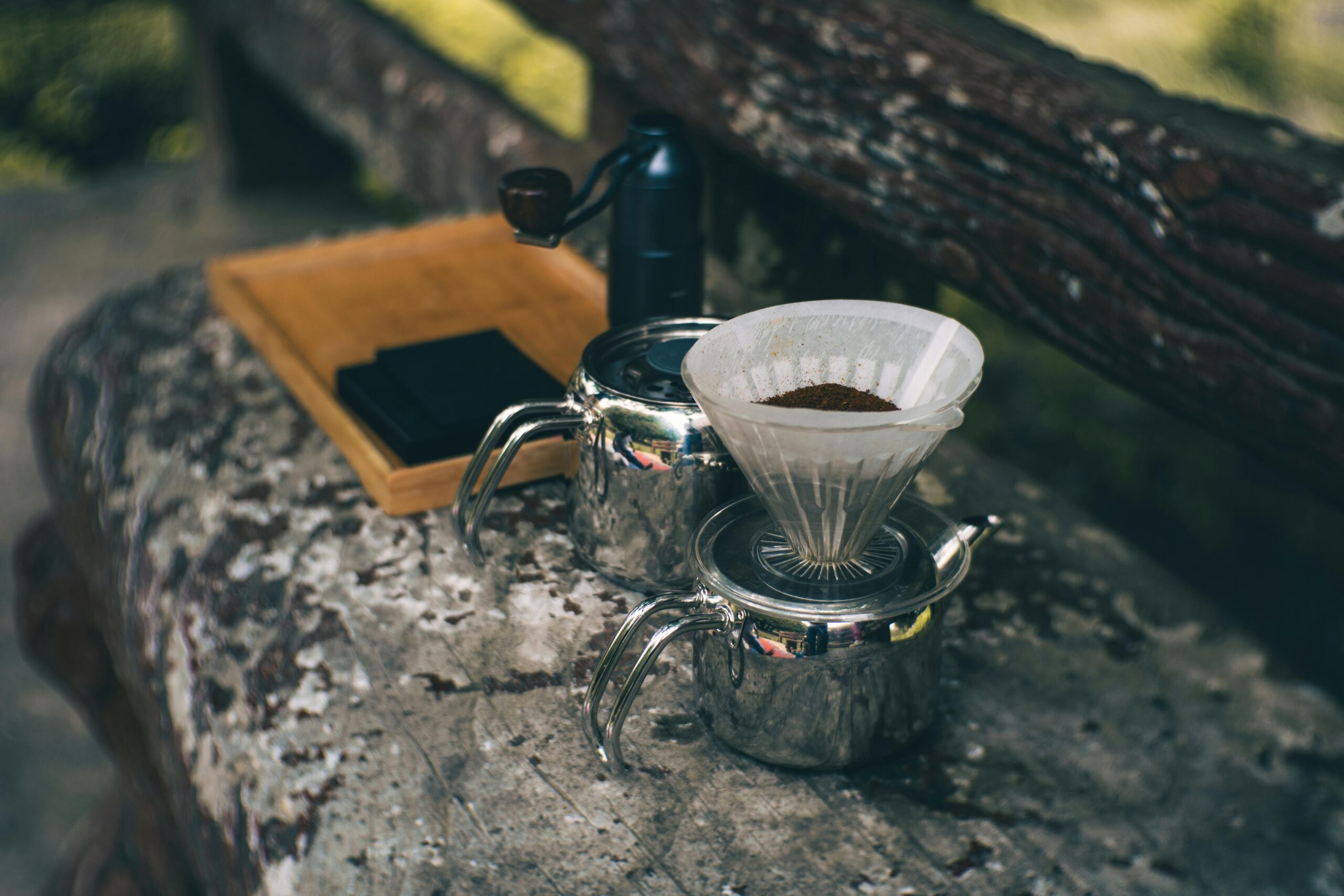 Rustic coffee brewing setup on a park bench, creating a warm and inviting outdoor experience.